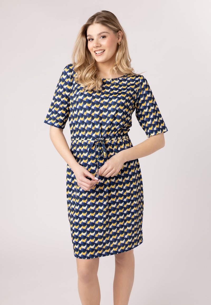 Kurzes ärmelloses Kleid in Blau mit einem gelb-weißen Wellenmuster. Mit einem Kordelzug in der Taille und knielanger Gestaltung. Glatte Stofftextur.