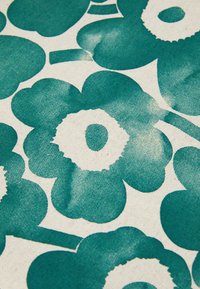 Tessuto floreale con un design in teal e crema che presenta grandi fiori stilizzati, accenti circolari e una superficie di cotone texturizzata.