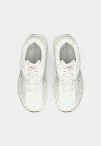 Para białych butów do biegania Nike z siateczkowymi detalami i sznurowadłami, widziana z góry na białym tle.