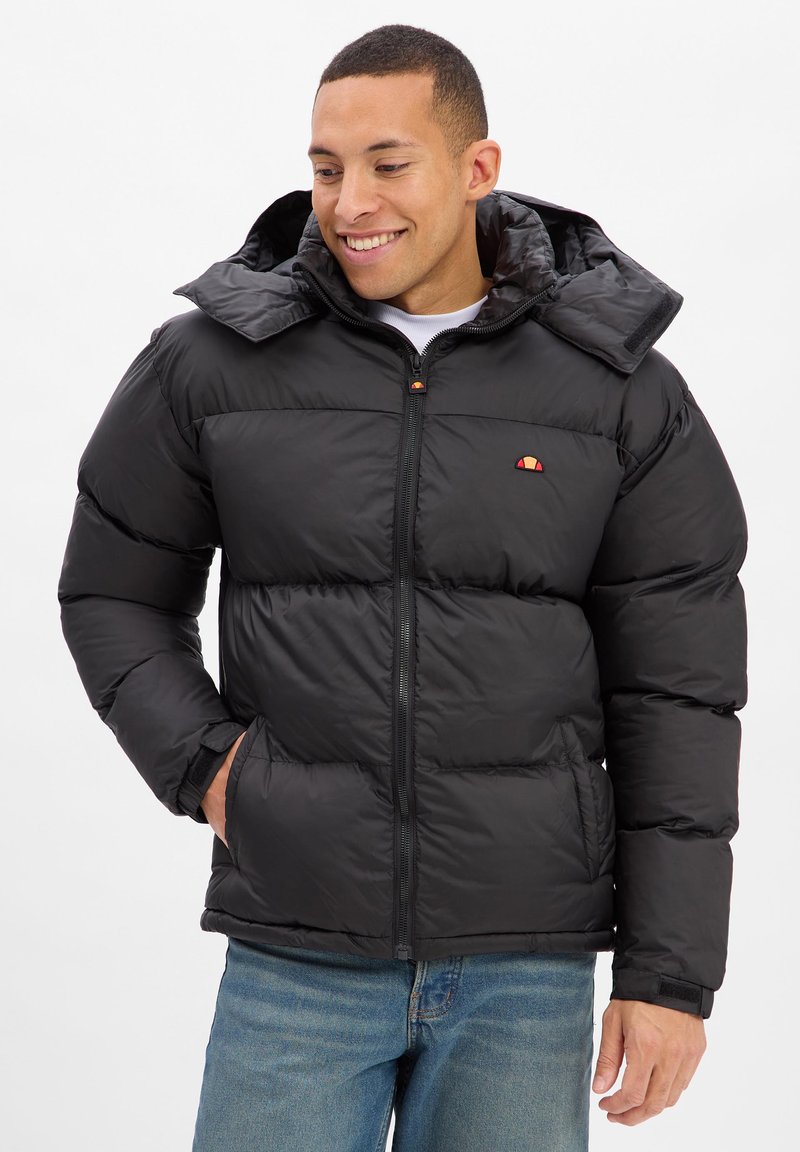 Schwarze Steppjacke mit Kapuze, vorn mit Reißverschluss, Seitentaschen und kleinem Logo auf der Brust. Strukturierte, gesteppte Optik.