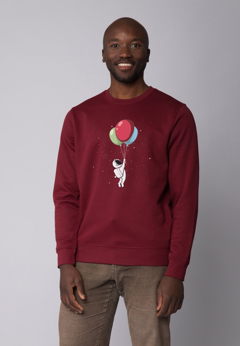 Bordeaux sweatshirt met een afbeelding van een astronaut die kleurrijke ballonnen vasthoudt. Heeft ribbelmanchetten en een ribbelzoom, en voelt zacht aan.