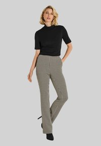 Zwarte korte mouwen coltrui gecombineerd met hooggetailleerde, aansluitende broek met een zwart-wit houndstooth patroon.