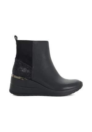 Bottine noire à la cheville avec talon compensé, panneau arrière texturé scintillant, languette au talon et finition en cuir lisse sur l'avant et les côtés.