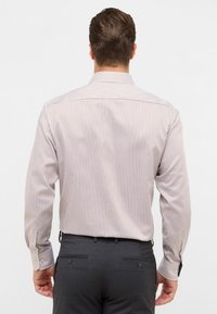 Lysfarvet stribet skjorte med lange ærmer, der har tynde lodrette striber i beige og brunt, samt en klassisk knap-ned krave.