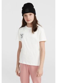 Vit t-shirt i bomull med korta ärmar som har svart text "Women of the Wave" på vänster bröst. Tillsammans med rosa sweatpants och en svart mössa.