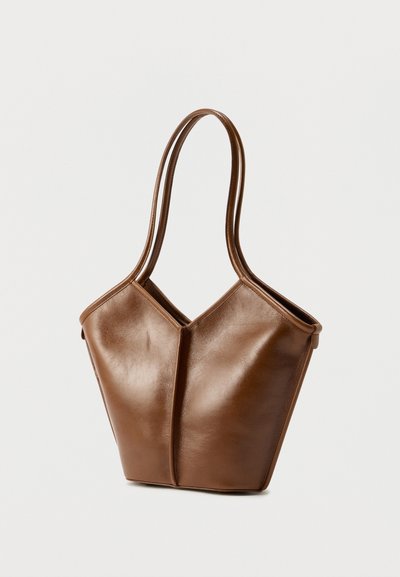 Καφέ δερμάτινη τσάντα tote με μοναδικό σχεδιασμό σε σχήμα V, δύο μακριές λαβές και λεία υφή με μινιμαλιστικές λεπτομέρειες.