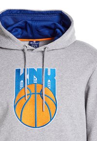 Felpa grigia con interno in rete blu e accenti arancioni. Presenta un logo di basket ricamato in modo prominente in arancione e blu.