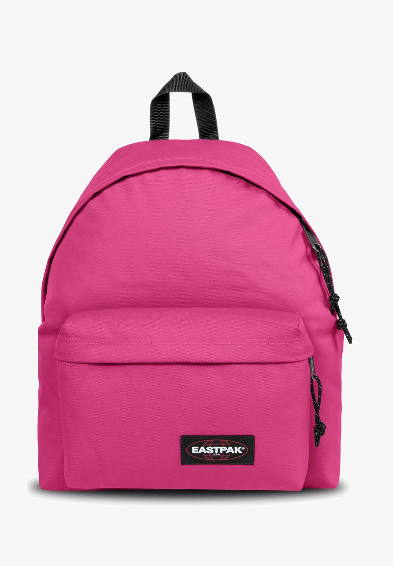 Mochila de tela rosa con forma redondeada, bolsillo frontal con cremallera y un parche negro con el logotipo. Correas ajustables negras en la parte superior.