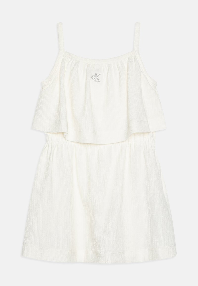 Λευκό αμάνικο φόρεμα με υφασμάτινη υφή, που διαθέτει πολλαπλές στρώσεις στο κορσέ και ελαστική μέση, διακοσμημένο με ένα μικρό κεντημένο λογότυπο.