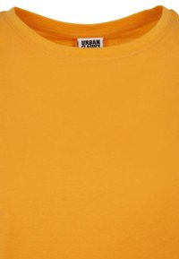 Keltainen puuvillapaita, jossa on pyöreä kaula-aukko ja lyhyet hihat. Materiaali näyttää sileältä ja siistiltä. Tunniste näkyvissä kauluksessa.