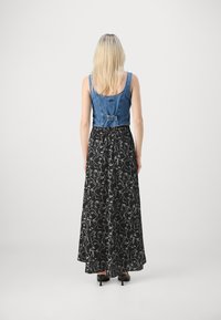 Corsage en denim au design ajusté associé à une jupe noire fluide avec un motif abstrait blanc. Vue de dos mise en avant.