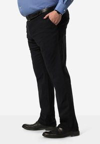 Pantaloni neri a gamba dritta con tasche laterali, realizzati in un tessuto liscio. Indossati con una camicia azzurra con bottoni e scarpe nere, con finitura lucida.