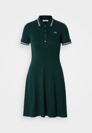 Tume roheline polo kleit lühikeste varrukatega, triibuliste äärtega, nööpide rida ja laienev seelik. Kangas tundub sile ja kergelt läikiv.