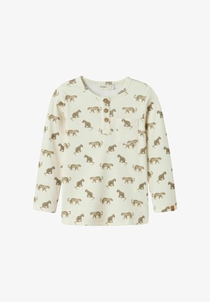 Camicia a maniche lunghe in tessuto a coste color crema con stampa animale marrone, dotata di tre bottoni in legno e una piccola tasca sul lato sinistro del petto.
