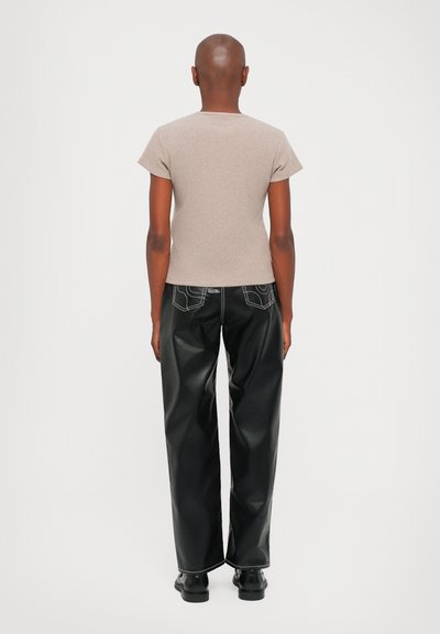 Fitted light brown t-shirt with short sleeves paired with black faux leather wide-leg pants featuring back pockets and white stitching.