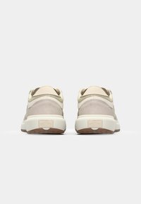 Lys beige sneakers med semsket og lærdetaljer. Rund hæl, tekstureret sål og subtil logo-detail på bagsiden. Minimalistisk design.