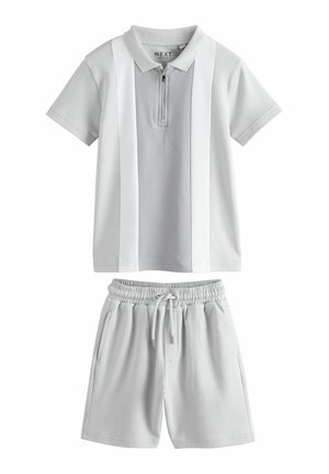 Graues Polo mit kurzen Ärmeln, Frontreißverschluss und vertikalen weißen Streifen, kombiniert mit hellgrauen Shorts mit elastischem Bund und Kordelzug.