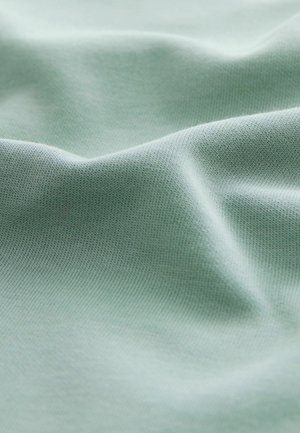 Teren de culoare verde deschis, cu o suprafață netedă, ușor texturată și elasticitate subtilă, având pliuri delicate și o cădere moale.