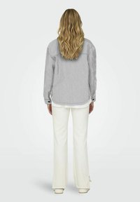Gestreiftes Button-Down-Hemd in Grau und Weiß, mit lockerer Passform, umgeschlagenen langen Ärmeln und einem Rückeneinsatz, kombiniert mit weißen, ausgestellten Hosen.