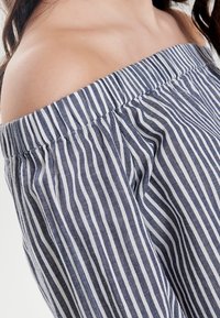 Off-the-shoulder top featuring vertical navy and white stripes, elasticized neckline, and soft, lightweight fabric.