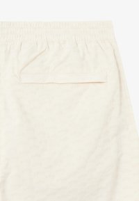 Shorts couleur crème avec une taille élastique, dotés d'une poche arrière et d'un motif subtil en tout genre du nom de la marque "BLKVIS".