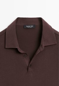 Bordeaux polo shirt met een zachte textuur, twee knoopsluitingen en een klassieke kraag. Etiket leest "Massimo Dutti, gemaakt in Marokko."