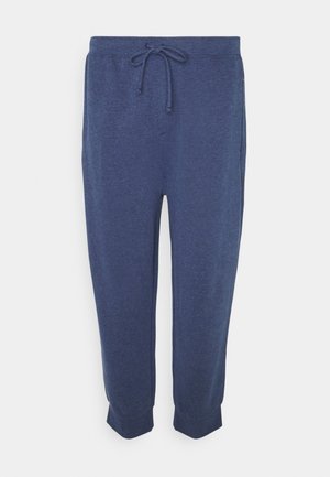 Blaue Jogginghose mit elastischem Bund und Kordelzug, schmal zulaufenden Beinen und gesäumten Bündchen vor einfarbigem Hintergrund.