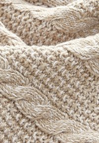 Nahaufnahme von beigem, gestricktem Wolle mit geflochtenen und strukturierten Maschenmustern, die eine gemütliche, warme Stoffoberfläche erzeugen.