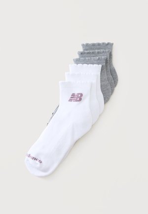 Cinq paires de chaussettes courtes, trois grises et deux blanches avec des logos New Balance bordeaux, disposées en pile décalée sur fond blanc.