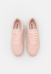 Paire de baskets texturées rose clair avec lacets, vue de dessus sur fond blanc.