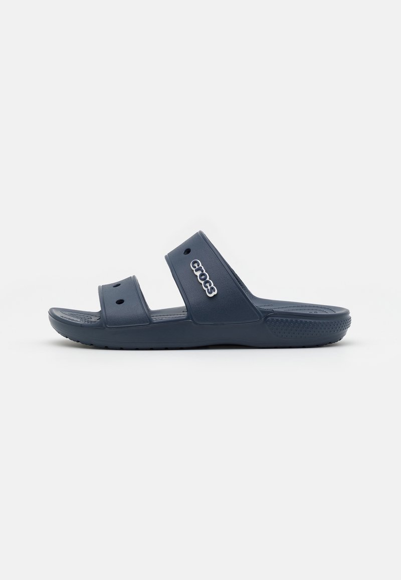 Sandale slide bleu marine Crocs avec deux brides et des trous de ventilation, avec le logo Crocs sur la bride supérieure, vue de côté.
