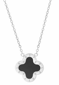 Collar de cadena de plata con un colgante en forma de trébol con un centro negro y letras grabadas alrededor del borde. Textura suave.