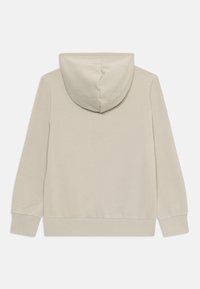 Beige huppari pehmeällä tekstuurilla, jossa on naruilla säädettävä huppu, pitkät hihat sekä ribbireunat hihansuissa ja helmassa. Minimalistinen muotoilu ilman koristeluita.