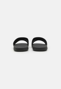Sorte slidesandaler med flade såler, brede stropper og en struktureret fodseng. Fremstillet af syntetisk materiale med et enkelt, minimalistisk design.