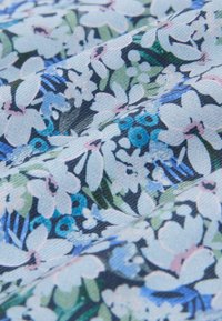 Tela floral en tonos de azul y verde, con una variedad de flores sobre un fondo claro, con detalles intrincados y textura.