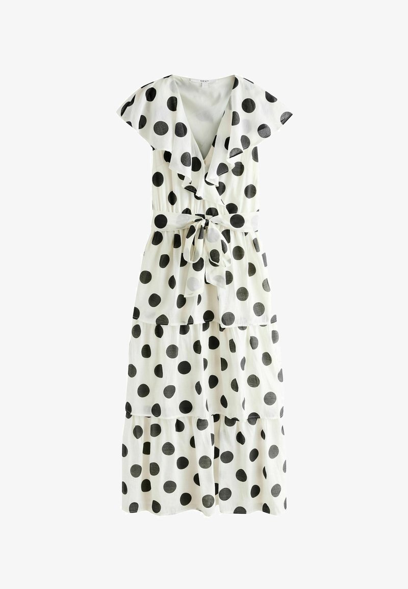 Robe midi à étages blanche à pois noirs, manches courtes volantées, col en V profond et ceinture nouée assortie à la taille.