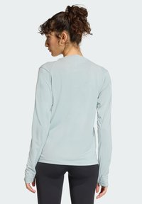 Jasnoniebieska bluzka z długim rękawem wykonana z miękkiego, elastycznego materiału. Posiada okrągły dekolt i dopasowane rękawy, zaprojektowana do aktywnego noszenia.
