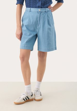 Hellblaue Jeansshorts mit weißen vertikalen Streifen, flacher Vorderseite, umgeschlagenem Saum und zwei seitlichen Taschen. Kombiniert mit weißen Sneakers.