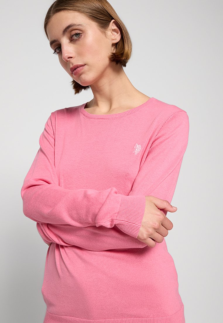 Maglione rosa a maniche lunghe realizzato in tessuto morbido. Presenta polsini e orlo a costine, con un piccolo logo ricamato sul petto sinistro.
