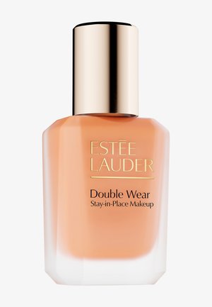 Estee Lauder Double Wear foundation i en klar glasflaske med et kantet design. Låget er skinnende guld; produktets farve er en blød fersken.