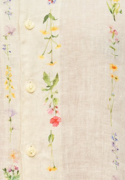 Λινό πουκάμισο σε ανοιχτό μπεζ χρώμα με κάθετη κεντημένη διακόσμηση με λουλούδια σε διάφορα χρώματα και σχήματα, και κουμπιά σε εκρού χρώμα.