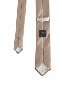 Beige strukturierte Krawatte mit sechseckiger Spitze, innen mit floralem Muster ausgekleidet und einem schwarzen Etikett mit der Aufschrift "NEXT Occasion".