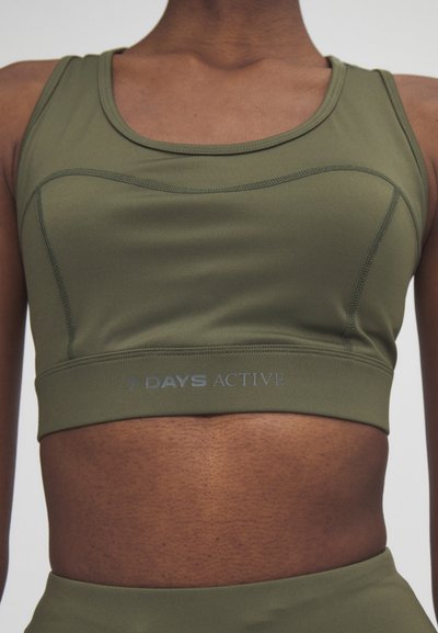 Olive green sports bra with a seamless design and contrasting stitching. Features "7 DAYS ACTIVE" logo on the elastic band below the bust.