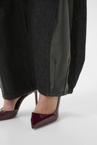 Black denim pants with shiny black leather side panels, paired with patent burgundy high heels featuring a pointed toe design.