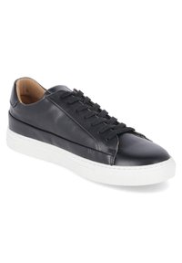 Black leather sneaker with a smooth texture, white rubber sole, round toe, and six eyelet lace-up design. Minimalist style with subtle stitching accents.