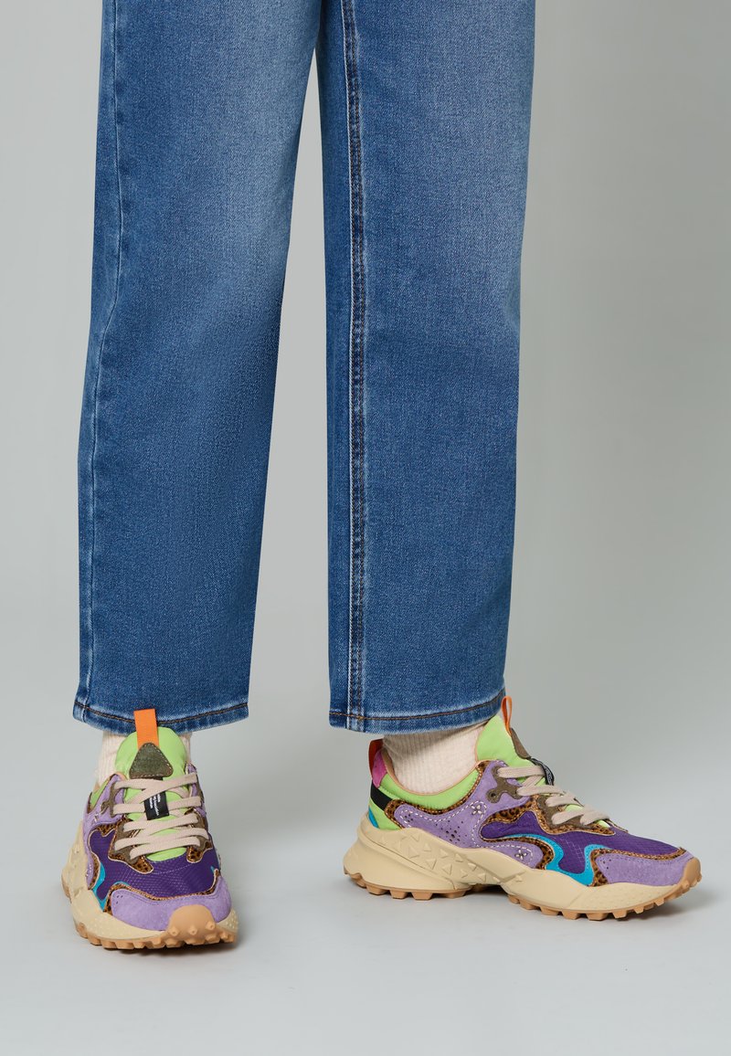 Mehrfarbige Sneaker aus einer Mischung aus lila, grün und beigen Materialien. Strukturierte Akzente und eine robuste Sohle mit Grip-Profil.