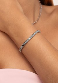 Silberarmband mit geflochtenem Design, glatter Textur und schlankem Profil, präsentiert an einem Handgelenk mit hellem Hautton.