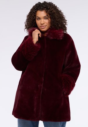 Bordeaux nep-vachtjasje met een zachte textuur, voorzien van een kraag en manchetten van vacht, en zijzakken. Rechthoekige snit.