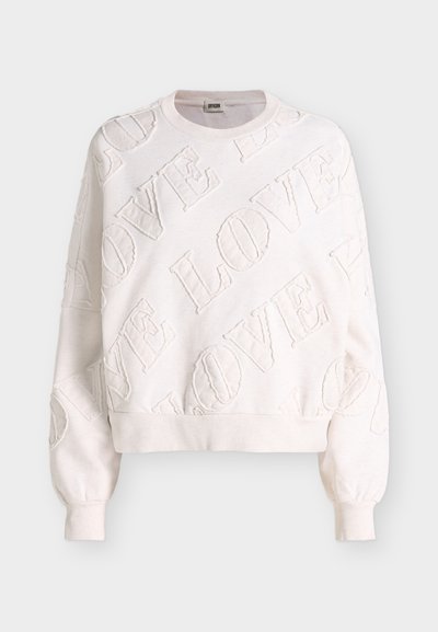 Sweat-shirt blanc à manches longues avec poignets et base côtelés, comprenant des lettres en relief texturées formant le mot « LOVE » sur le tissu.