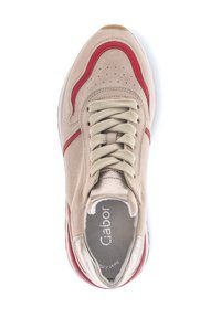 Beige suede sneaker met rode leren accenten, geperforeerde neus en beige veters. Rubberen buitenzool en gevoerde binnenzool zichtbaar.